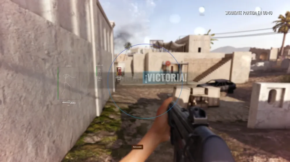 First-person shooter video game screenshot. A hand holds a rifle aiming towards a sandy, Middle Eastern-style village. The word ¡VICTORIA! appears on screen, implying a win. The tone is intense and triumphant.