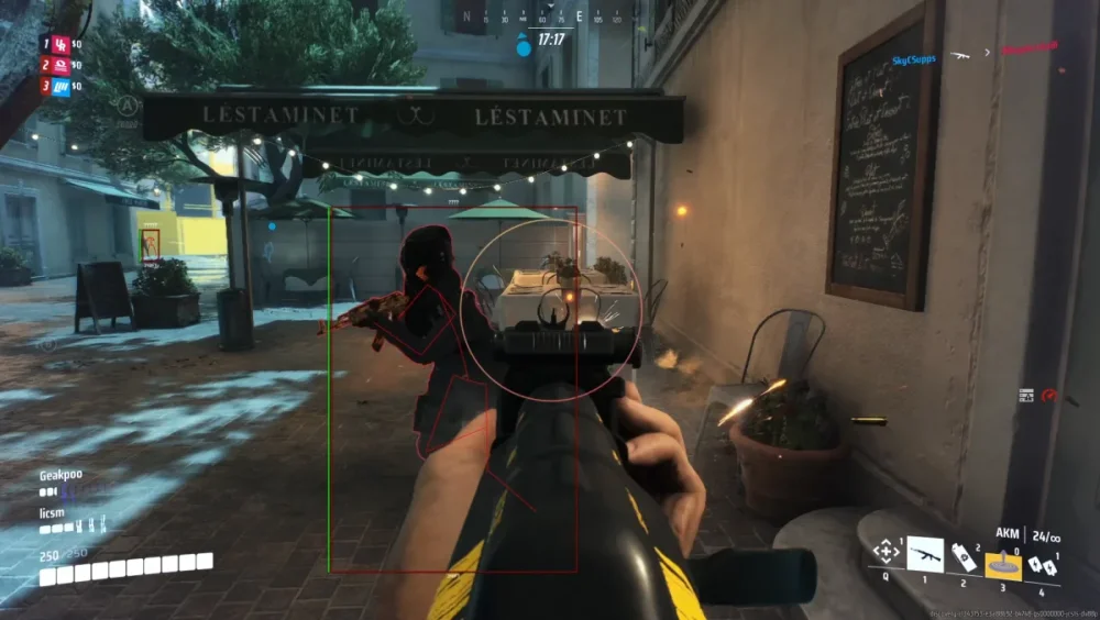 First-person shooter game scene in an urban cafe setting. A player aims an AKM rifle at an opposing character, surrounded by atmospheric lighting and foliage.